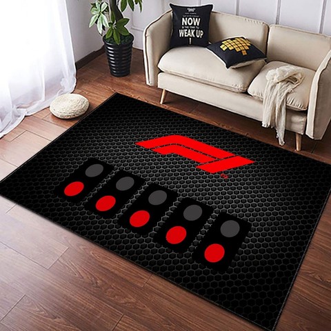 A large Formula One themed black mat with the ref F1 logo and a strip of 5 red lights waiting for the go go go, on a wooden floor with a couch behind.